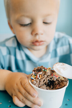 Blonde caucasian toddler eating chocolate ice cream with sprinkles