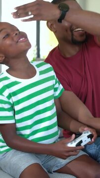 Vertical video: Reacting to game boy in green tee using white controller on couch, dad smiling