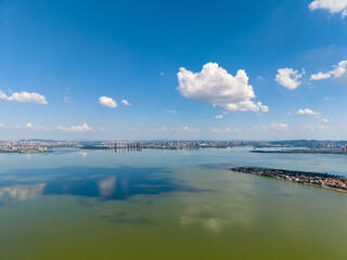 Aerial view of a city skyline on the water in Wuhan, China with a bright blue sky and clouds