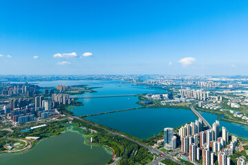 Obraz premium Aerial view of Wuhan China showcasing urban development along blue waters and green landscapes under a clear sky