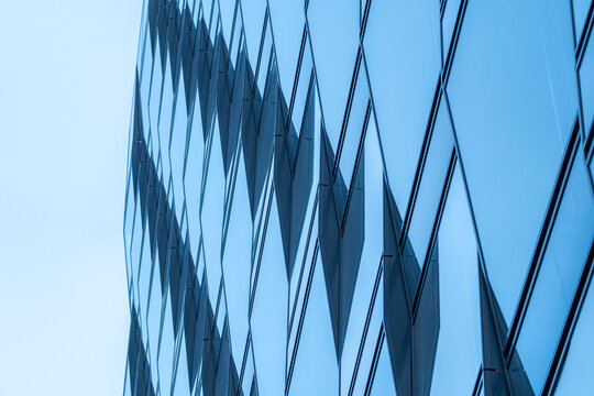 Urban modern architecture building facade of glass with abstract pattern showing reflection into wide sky creating minimal background copyspace for design
