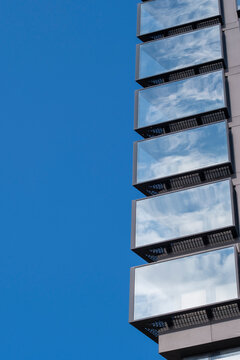 Urban modern architecture building facade of glass with balcony pattern rising into open sky creating minimal copyspace for design and advertising