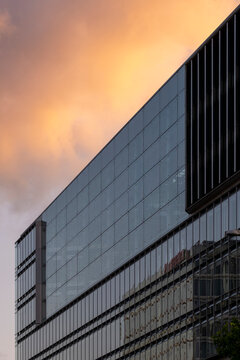 Urban modern architecture building facade of glass office tower showing reflection under sunset sky with clean copyspace for corporate background use