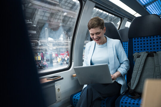 Businesswoman working on laptop during train journey in wagon compartment