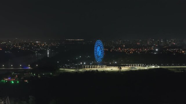 Breathtaking aerial view of the brightly lit Yup Star Ferris wheel in Foz do Igua&ccedil;u, Brazil, shining against the night skyline with vibrant city lights. Triple frontera landmark