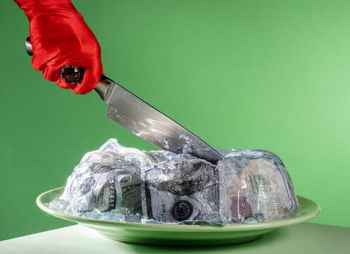 Red gloved hand cutting a jelly cake filled with money and banknotes