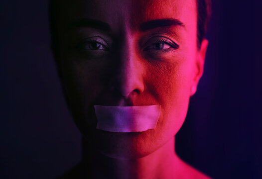 Portrait of person with tape over mouth symbolizing censorship and silence