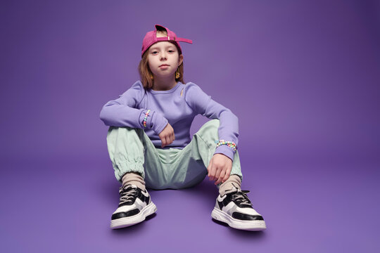 Trendy urban style girl in studio with cap and sneakers
