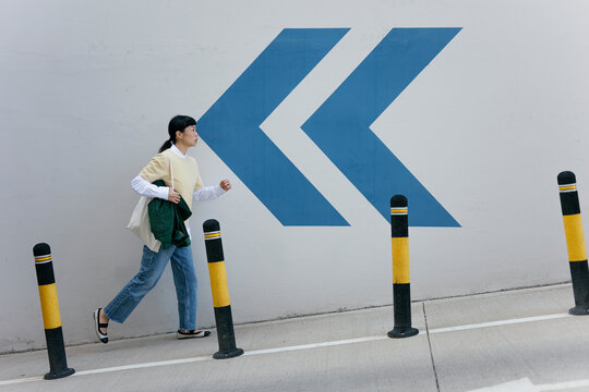 Woman walking on urban sidewalk in casual outfit with arrow graphic