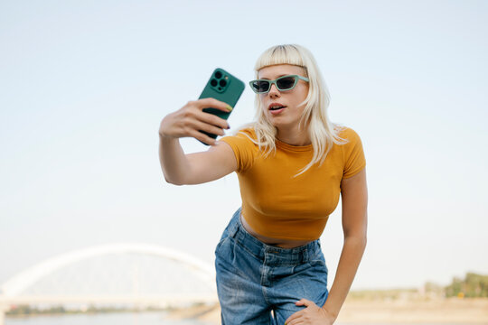 Hipster with sunglasses taking selfie outdoors in urban setting