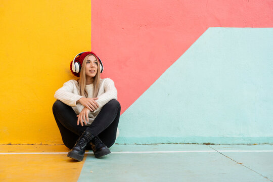 Woman sitting on colorful geometric background with headphones