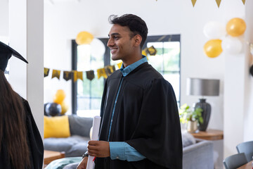 Obraz premium Asian friends celebrating graduation inside decorated living room with gowns balloons, diploma