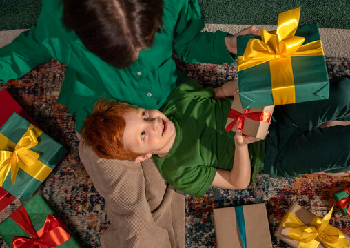 Red-haired boy and mother exchanging gifts together at home