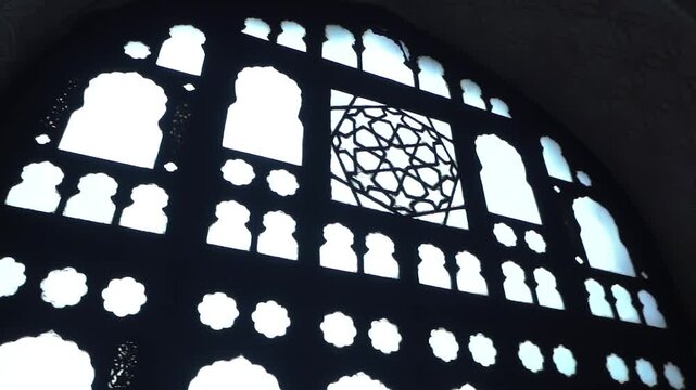 Intricate jaali window with geometric lattice pattern inside a historic Indian monument, showcasing Mughal-influenced Indo-Islamic architecture and dramatic light and shadow.