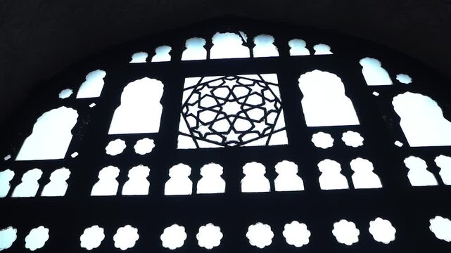 Intricate jaali window with geometric lattice pattern inside a historic Indian monument, showcasing Mughal-influenced Indo-Islamic architecture and dramatic light and shadow.