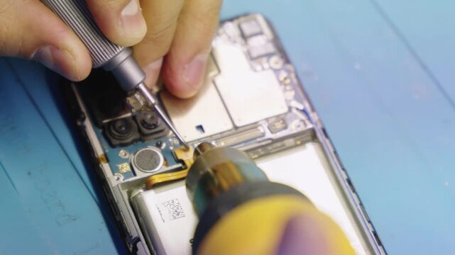 Technician fixing phone with screwdriver