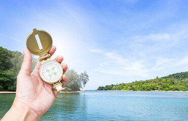 Compass in hand over tropical island background, Navigation tool for tourism and direction of travel