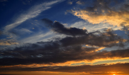 Obraz premium Dramatic sunset sky with golden clouds and deep blue twilight.