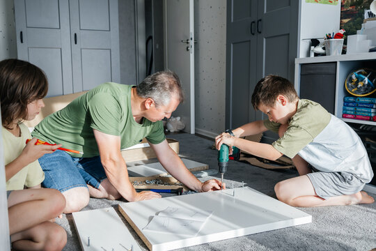 Father and sons assembling furniture, teamwork home improvement