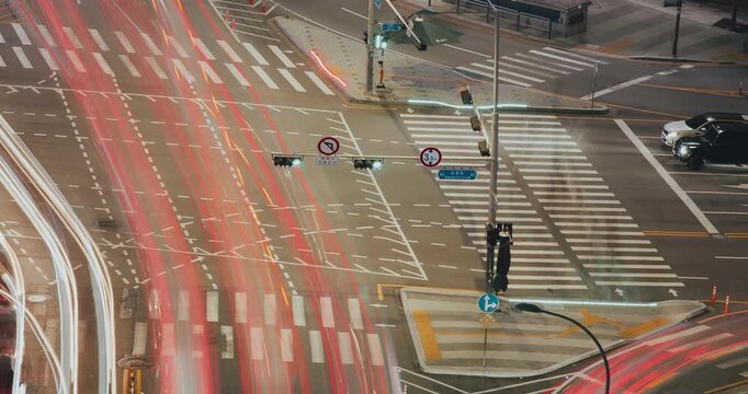 A vibrant urban traffic scene depicts cars maneuvering through intersections with changing traffic signals and dynamic motion blur effects. Time-lapse, Seoul, South Korea
