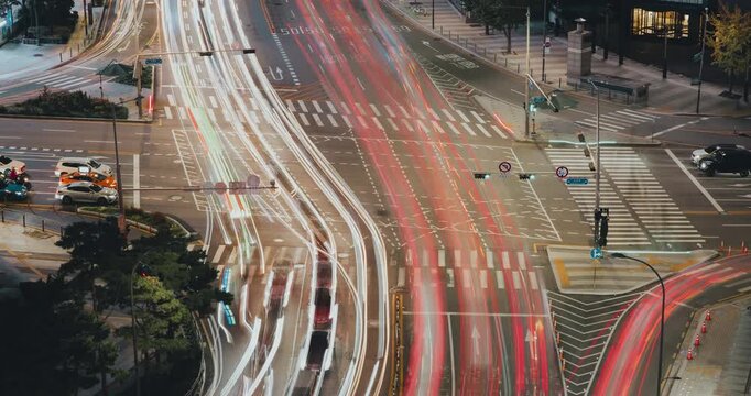 Urban traffic intersection captured at night with vehicles moving through illuminated signals and crosswalks, highlighting the vibrant city atmosphere. Time-lapse, Seoul, South Korea