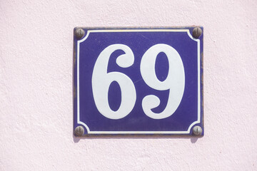 Blaues Hausnummernschild Nr. 69 auf weisser Hauswand, Deutschland