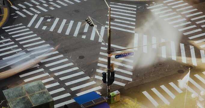 An urban crosswalk scene captures the traffic light changing as pedestrians start to cross the street while vehicles wait at the intersection. Time-lapse, Seoul, South Korea