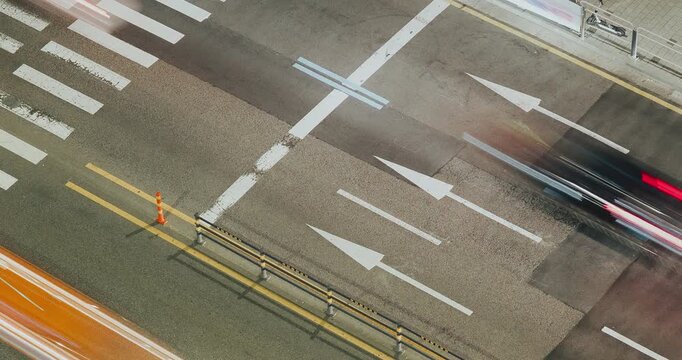 Vehicles traverse an urban street, highlighting the continuous flow of traffic with visible lane markings and blurred motion effects. Time-lapse, Seoul, South Korea