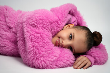 Young Girl in Pink Faux Fur Coat Lying Down and Smiling