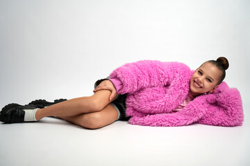 Young Girl in Pink Faux Fur Coat Lying Down and Smiling