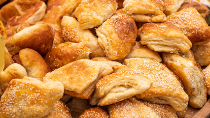 Golden brown sesame pastries on wooden tray