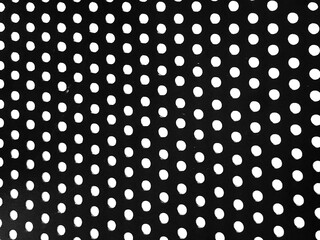 Perforated black metal sheet with symmetric white circular holes. Seamless dots pattern