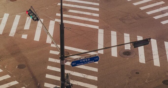 A traffic light transitions from red to green, highlighting crosswalk lines and street signs as vehicles begin to move through the intersection. Time-lapse, Seoul, South Korea