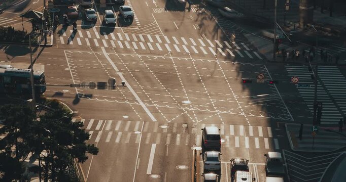 A bustling city intersection showcases vehicles navigating through lanes while pedestrians cross streets under changing traffic signals. Time-lapse, Seoul, South Korea