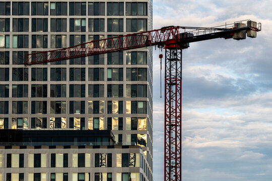 Evening Berlin highrise glass facade with windows glowing as modern crane marks urban architecture and ongoing construction activity