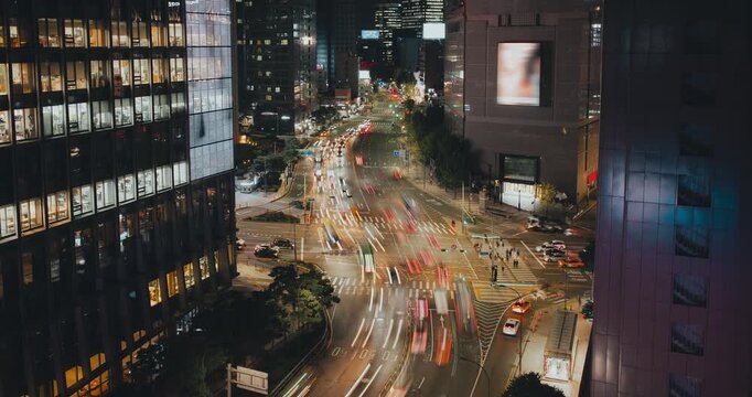 A bustling urban intersection at night with moving vehicles, glowing skyscrapers, and vibrant street lights enhancing the lively cityscape. Time-lapse, Seoul, South Korea