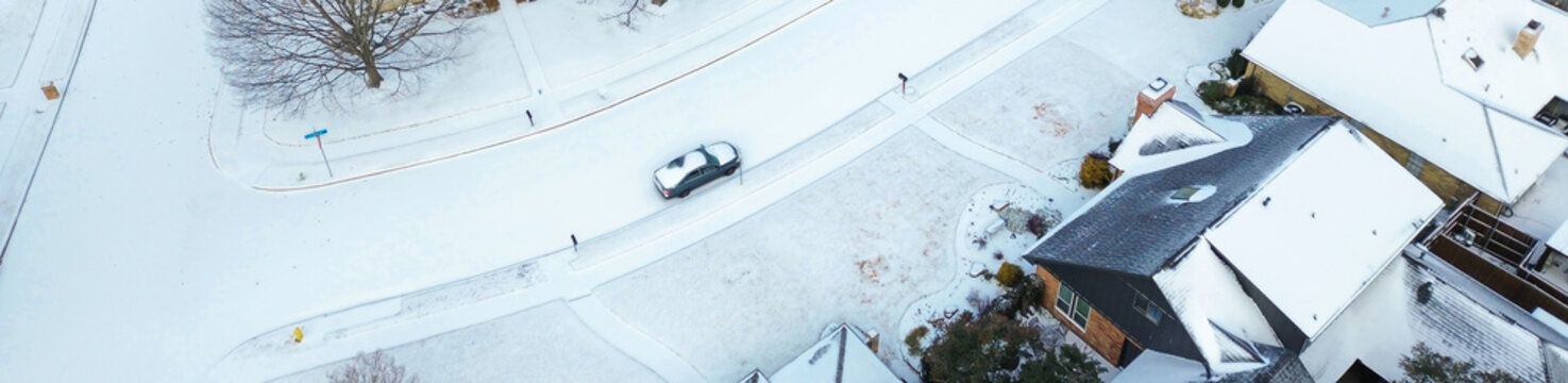 Panorama aerial view subdivision near Parkway Boulevard in the midst of Winter Storm Fern rooflines, icy roads, sparse vehicle movement. Leafless trees, pale lawns deepen winter hush, Coppell, TX