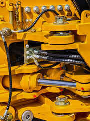 Hydraulic system components on heavy machinery in a construction area during daytime