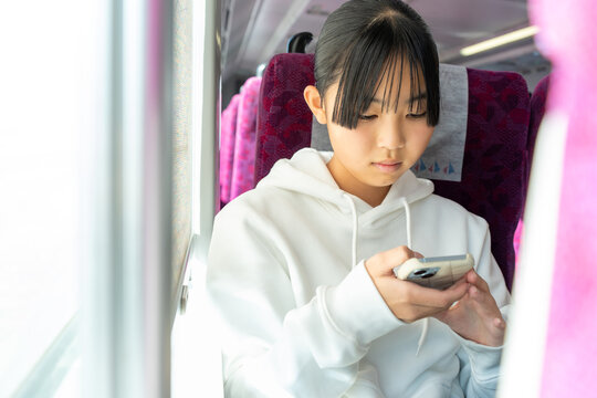 電車内でスマホを使う女子学生