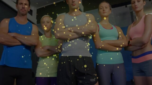 Camera rising over fitness team with golden particles drifting and middle trainer issuing challenge
