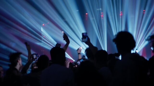 Music audience surrounded by green and red and blue laser lights during energetic live show