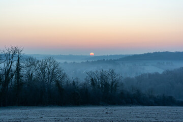 Winter landscape at sunrise with mist and frost