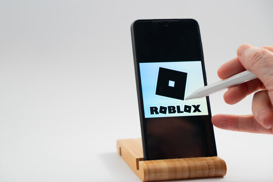 Hand interacting with roblox application on mobile phone using a digital stylus