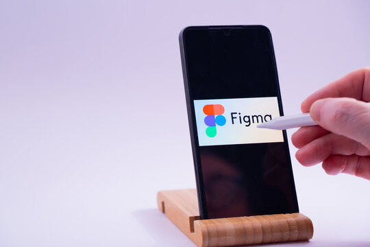Hand interacting with figma uiux design software on a smartphone with a stylus pen