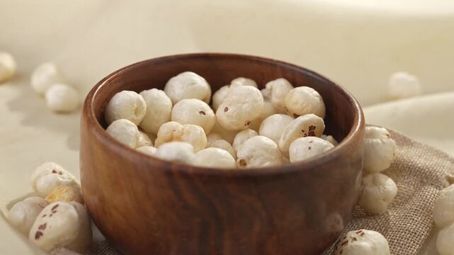 Makhana falling on wooden bowl closeup shot.