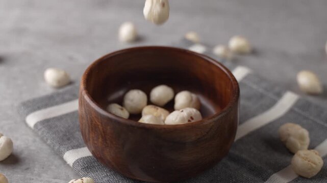 Makhana falling on wooden bowl closeup shot.