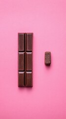 Dark Chocolate Bar Segments with Toppings on a Pink Glittery Background Viewed from Above