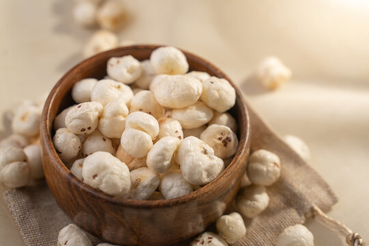 Phool Makhana, Fox Nut, Lotus Pops Seeds, Gorgon nut, Euryale Ferox on a wooden bowl with beige background.