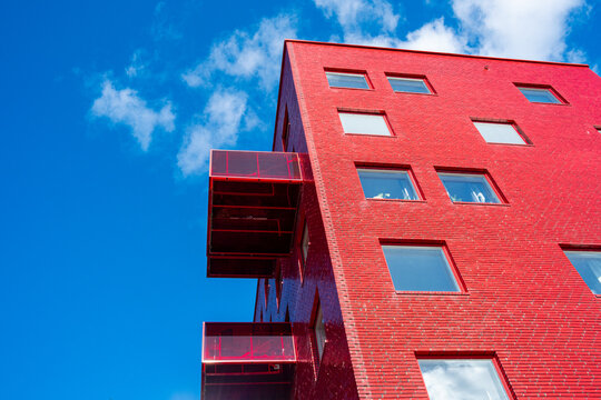 Modern architecture apartment residential building facade with red urban balcony under sky seen from low angle perspective upward exterior