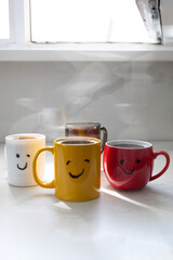 Obraz premium Four mugs of hot coffee sit on a table in a bright room. Steam rises from the mugs as sunlight streams through the window. The scene shows a cozy morning moment.